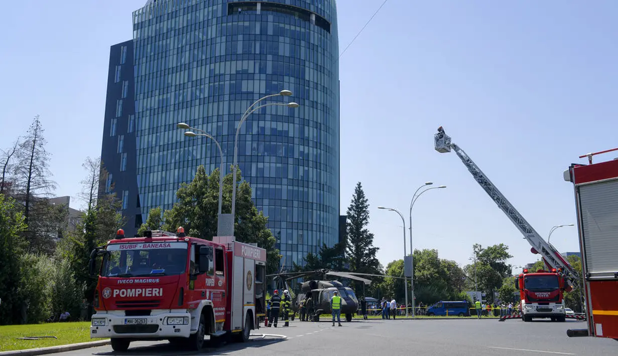 Petugas pemadam kebakaran, dari atas, memeriksa helikopter Black Hawk AS yang mendarat darurat di boulevard yang sibuk, di Bucharest, Kamis (15/7/2201). Helikopter yang ambil bagian dalam persiapan hari Penerbangan Rumania itu mendarat darurat karena masalah teknis. (AP Photo/Andreea Alexandru)