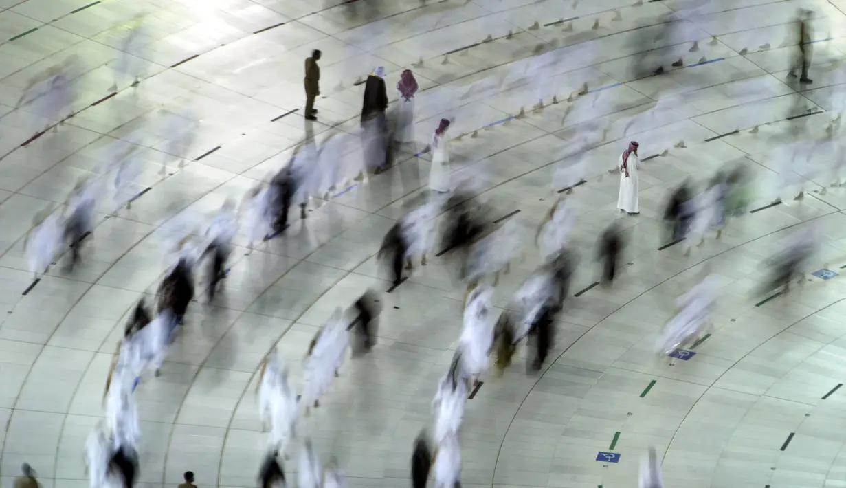 Dalam foto yang diambil dengan kecepatan rana lambat ini menunjukkan anggota keamanan memastikan jemaah umrah menerapkan jaga jarak untuk membantu mengekang penyebaran virus corona COVID-19 saat tawaf mengelilingi Ka'bah di Masjidil Haram, Mekkah, Arab Saudi, Selasa (13/4/2021). (AP Photo/Amr Nabil)