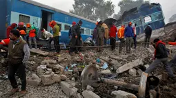 Petugas mencari korban yang masih tersisa di antara bangkai kereta api setelah terjadi kecelakaan di Pukhrayan, Kanpur, India (21/11). Menurut keterangan kepolisian setempat, korban yang meninggal tercatat lebih dari 100 orang. (Reuters/ Jitendra Prakash)