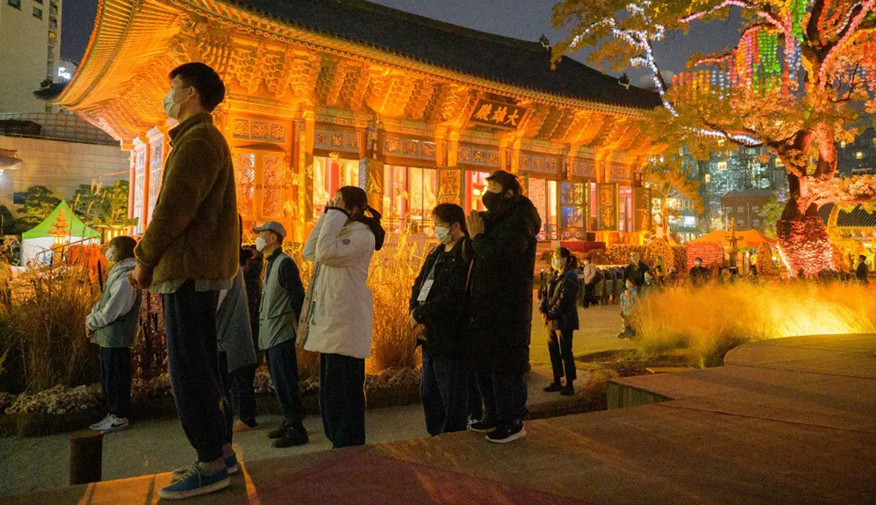 Warga berdoa di Kuil Jogyesa pada malam sebelum para siswa mengikuti ujian masuk universitas atau suneung, Seoul, Korea Selatan, 17 November 2021. Lebih dari setengah juta siswa akan mengikuti suneung di Korea Selatan. (Anthony WALLACE/AFP)