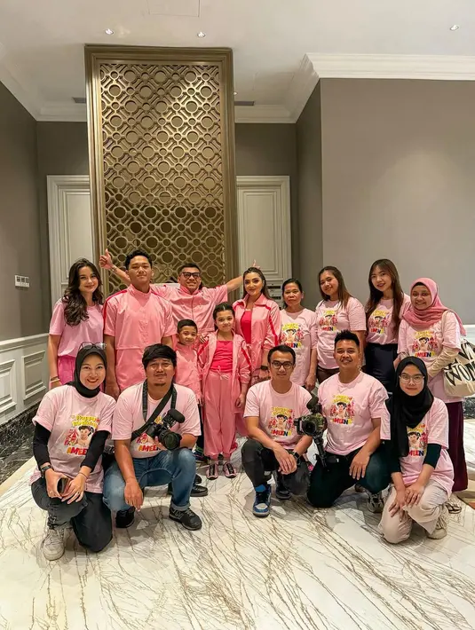 Ashanty tampil kompak dengan Arsy, yaitu mengenakan tank top pink tua, ditumpuk dengan outer ber-zip dengan sentuhan garis merah, dan jogger pants berwarna pink senada. Para pria; Anang, Azriel, dan Arsya tampil kompak mengenakan busana pink serasi dengan kerah tinggi dan celana panjang hitam. [Foto: Instagram/ashanty_ash]