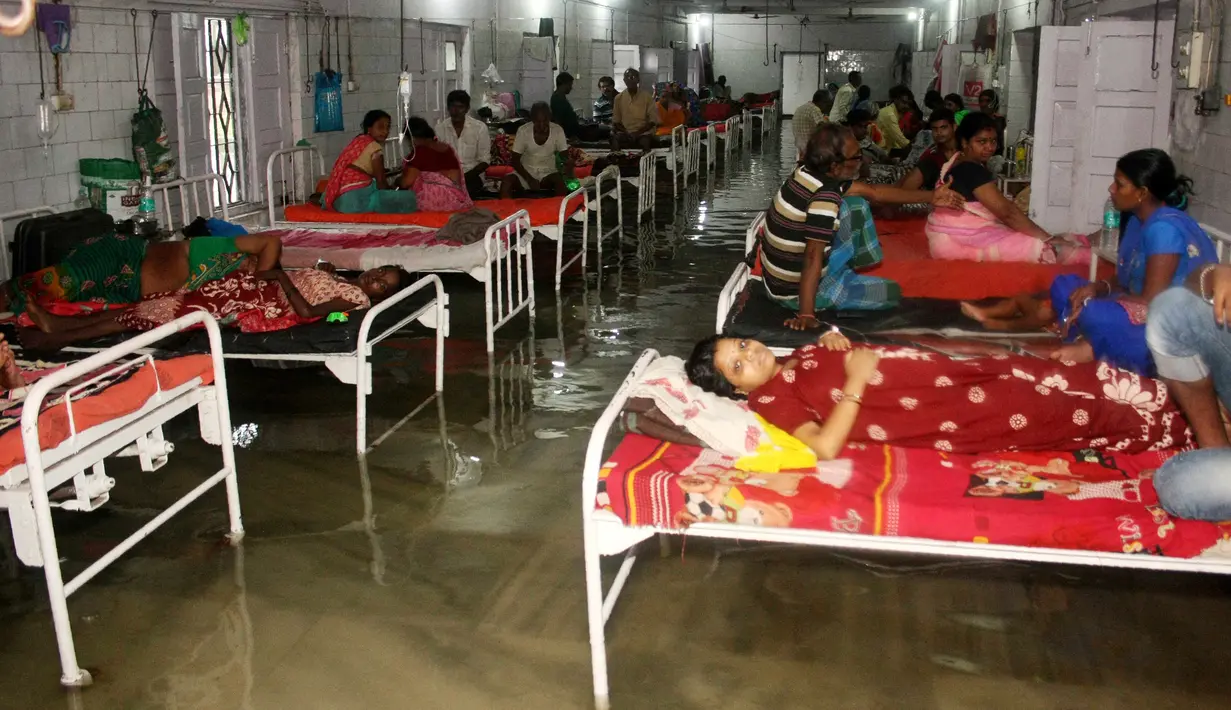 Pasien dan anggota keluarganya berada di dalam bangsal yang tergenang banjir di Nalanda Medical College Hospital, daerah Bihar, India, 29 Juli 2018. Rumah sakit itu digenangi air kotor dengan sejumlah ikan terlihat berenang memenuhi lantai. (AFP PHOTO)