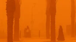 Perempuan berjalan di tengah badai debu parah di Kota Kuwait pada 23 Mei 2022. Gumpalan debu besar yang melayang di atas Kuwait telah mengurangi visibilitas menjadi hampir nol di jalan-jalan hampir sepanjang hari di seluruh negeri. (Yasser Al-Zayyat / AFP)