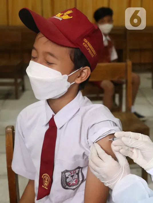 Ekspresi seorang siswa saat disuntik vaksin COVID-19 Pfize di SDN Panunggangan 5, Pinang, Kota Tangerang, Selasa (19/10/2021).  Pelaksanaan vaksinasi untuk pelajar usia 12 tahun ini dilakukan dalam rangka persiapan pelaksanaan pembelajaran tatap muka (PTM). (Liputan6.com/Angga Yuniar)