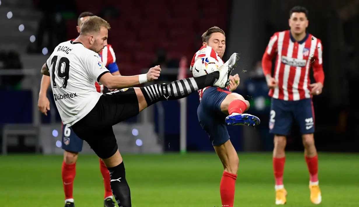 Gelandang Valencia, Uros Racic (kiri) bersaing dengan gelandang Atletico Madrid, Marcos Llorente pada jornada ke-20 Liga Spanyol di Wanda Metropolitano, Senin (25/1/2021) dini hari WIB. Atletico Madrid memetik kemenangan 3-1 atas Valencia. (PIERRE-PHILIPPE MARCOU/AFP)