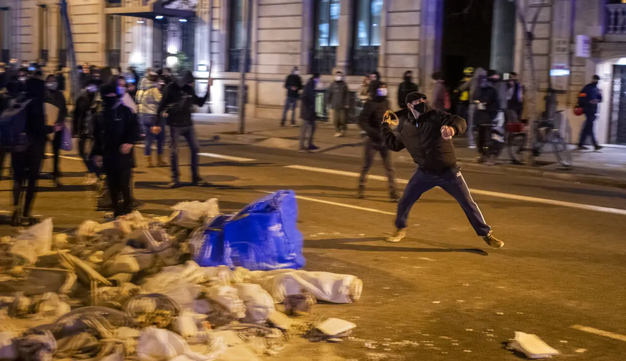 Demonstran bentrok dengan polisi saat memprotes penangkapan rapper Pablo Hasel di Barcelona, Spanyol, Selasa (16/2/2021). Aksi protes meletus di Spanyol setelah polisi menangkap Pablo Hasel yang menolak hukuman penjara karena menghina kerajaan dan memuji terorisme. (AP Photo/Emilio Morenatti)