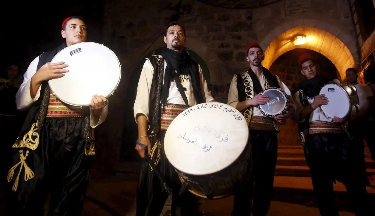 Pemuda Palestina membangunkan sahur menggunakan musik tradisional, di permukiman Hebron, Tepi Barat, 23 Juni 2015. Tradisi tersebut dilakukan secara turun-temurun untuk mempererat silaturahmi dan simbol kepedulian sesama muslim. (REUTERS/Mussa Qawasma)
