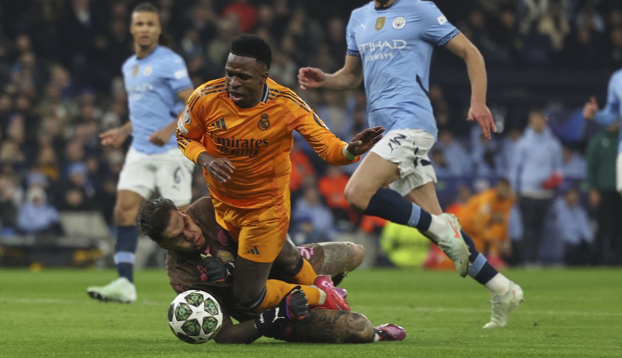 Pemain Real Madrid, Vinicius Junior jatuh saat terjegal kiper Manchester City, Ederson dalam laga leg 1 babak playoff Liga Champions 2024/2025 di Etihad Stadium, Manchester, Inggris, Rabu (12/02/2025) WIB. (AP Photo/Darren Staples)