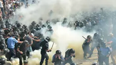 Demonstran menyerang polisi dengan bom asap dan granat gas air mata di depan gedung Parlemen Ukraina , Senin (31/8). Satu petugas tewas dan 90 lainnya terluka dalam aksi yang menentang perubahan UU dasar mengenai desentralisasi. (AFP PHOTO/Genya SAVILOV)