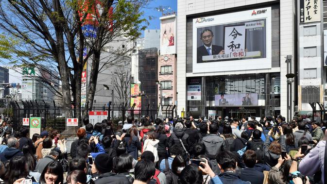 Orang-orang menonton layar besar yang menayangkan konferensi pers terkait pengumuman nama baru kekaisaran Jepang di Tokyo, Senin (1/4). Reiwa, menjadi nama era yang baru Jepang mulai 1 Mei 2019 setelah Kaisar Akihito turun takhta pada akhir April mendatang. (Kyodo News via AP)