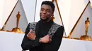 Aktor Chadwick Boseman berpose di karpet merah ajang Piala Oscar 2018, Los Angeles, Minggu (4/3). Pemeran utama Black Panther ini tampil bak raja dengan jas hitam dengan aksen perak yang melintang di bagian dada. (Jordan Strauss/Invision/AP)