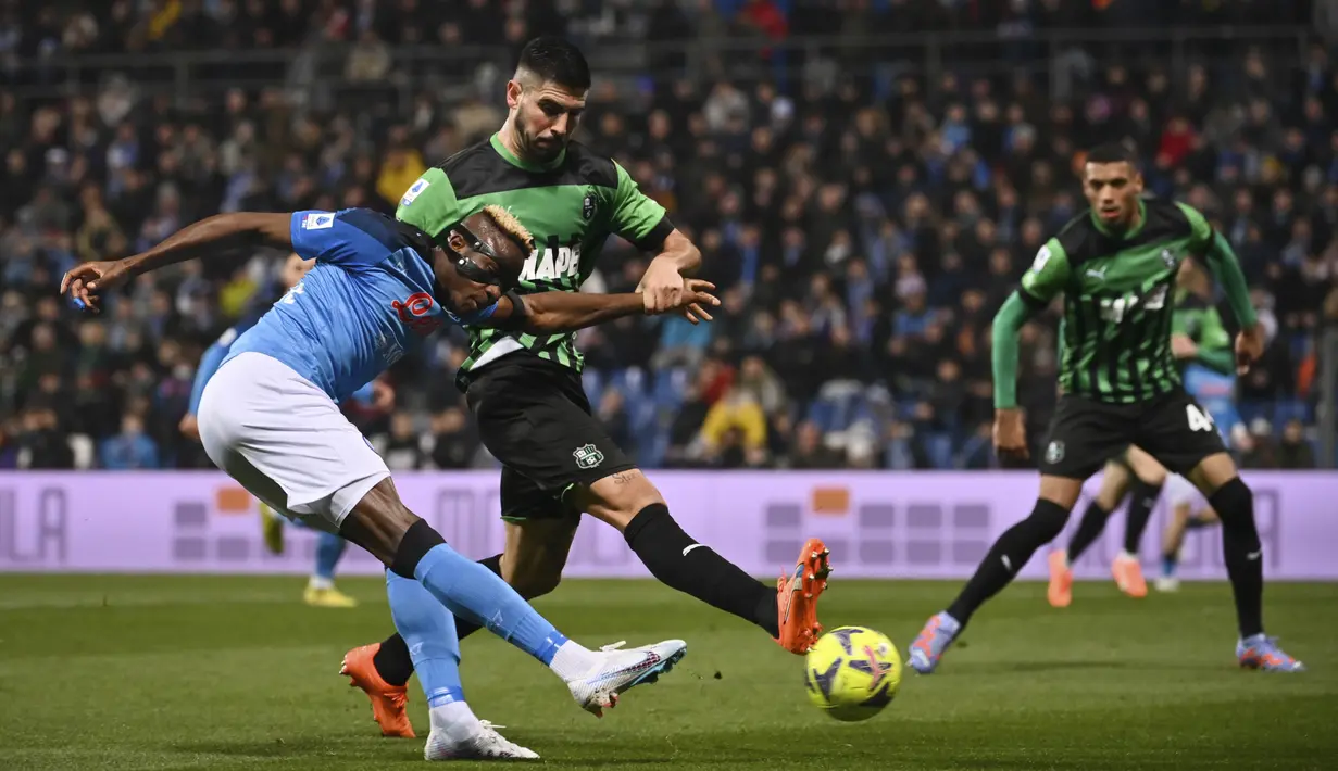 Pemain Napoli, Victor Osimhen (kiri) menendang bola dari sudut sempit ke gawang Sassuolo yang membuahkan gol dalam pertandingan pekan ke-23 Liga Italia 2022/2023 di Mapei Stadium, Sabtu (18/2/2023). (AFP/Marco Bertorello)