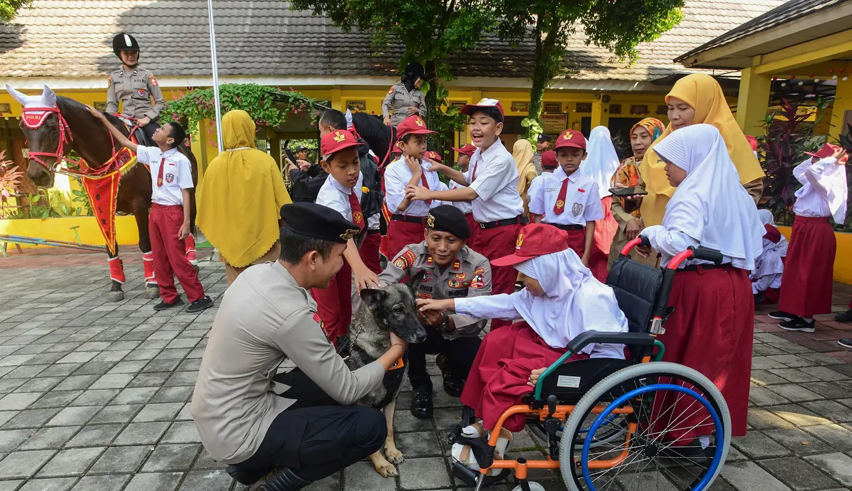 Salah satu siswa didampingi personel Direktorat Polisi Satwa (Ditpolsatwa) berinteraksi dengan anjing pelacak K-9 di Sekolah Luar Biasa Negeri (SLBN) kota Depok, Jawa Barat, Senin (2/6/2025). (merdeka.com/Arie Basuki)