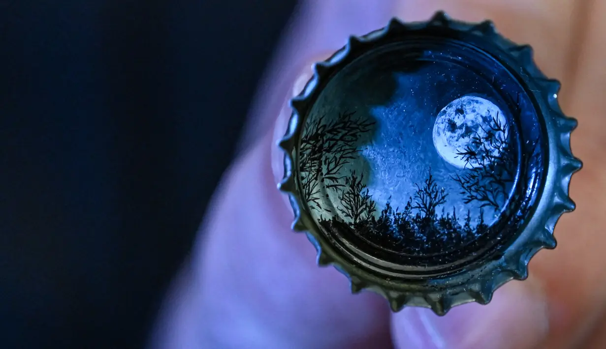 Tutup botol bergambar pemandangan bulan karya seniman mikro Hasan Kale, Istanbul, Turki, 23 Agustus 2019. Hasan Kale telah melukis lebih dari 350 objek selama kariernya. (OZAN KOSE/AFP)