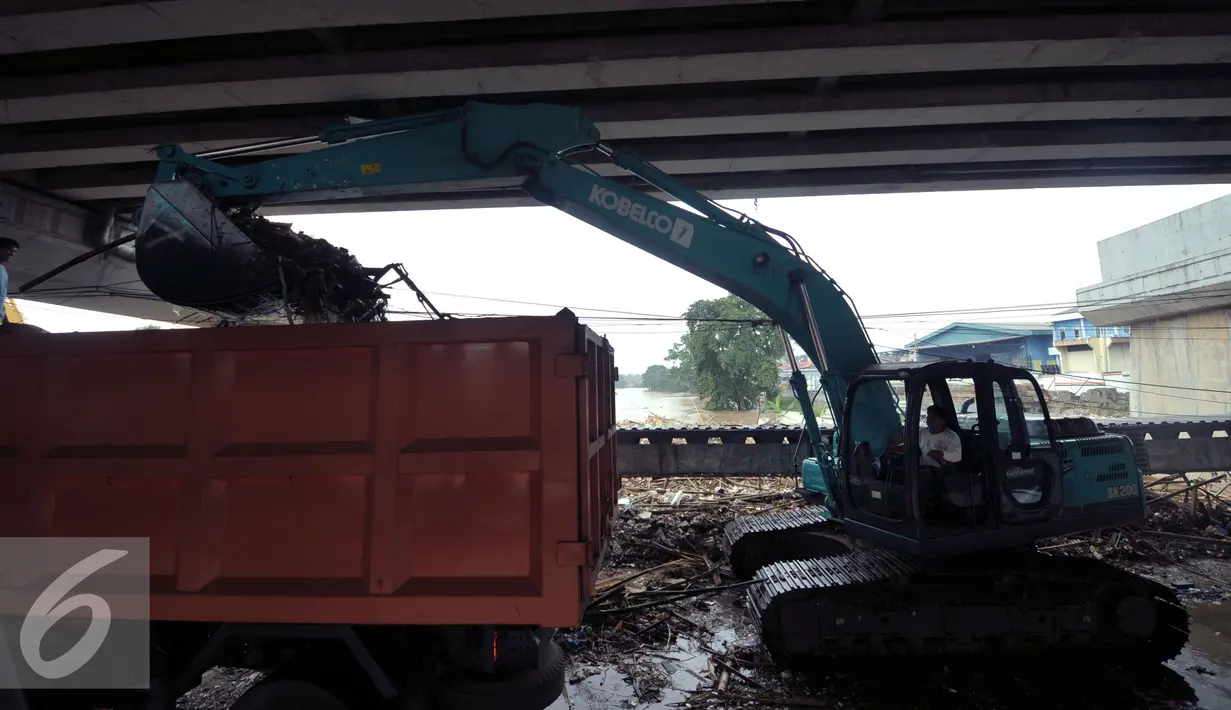Alat berat dan truk mengangkut tumpukan sampah di jembatan Rawajati Kalibata, Jakarta, Selasa (8/3/2016). Hujan yang mengguyur Bogor dua hari terakhir mengakibatkan banjir kiriman yang disertai sampah batang bambu. (Liputan6.com/Helmi Fithriansyah)