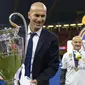 Pelatih Real Madrid, Zinedine Zidane, mengangkat trofi  usai memastikan diri sebagai juara Liga Champion dengan mengalahkan Juventus di Stadion Millennium, Cardiff, Sabtu (3/06/2017). Real Madrid menang 4-1. (AFP/ Filippo Monteforte)