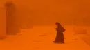 <p>Seorang perempuan melihat-lihat telepon saat berjalan di tengah badai debu yang parah di Kota Kuwait pada 23 Mei 2022. Kabut oranye tebal telah menyelimuti Kuwait pada hari Senin, menyebabkan penerbangan ke dan dari bandara internasional negara itu ditangguhkan sementara, kata regulator penerbangan sipil. (Yasser Al-Zayyat / AFP)</p>