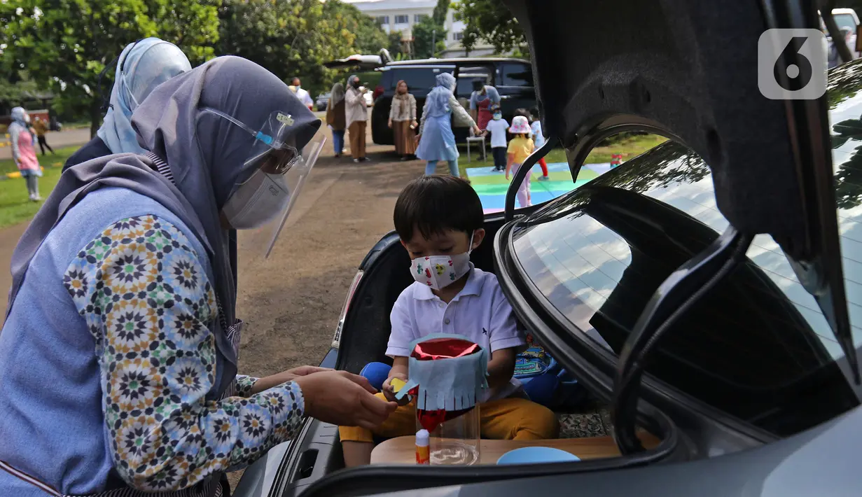 Siswa TK didampingi guru membuat miniatur bedug saat mengikuti proses pembelajaran secara Drive in Learning di area parkir Padepokan Pencak Silat Indonesia, Jakarta, Kamis (8/4/2021). Kegiatan ini juga untuk menyambut Ramadan dengan penuh rasa syukur dan kebahagiaan. (Liputan6.com/Herman Zakharia)