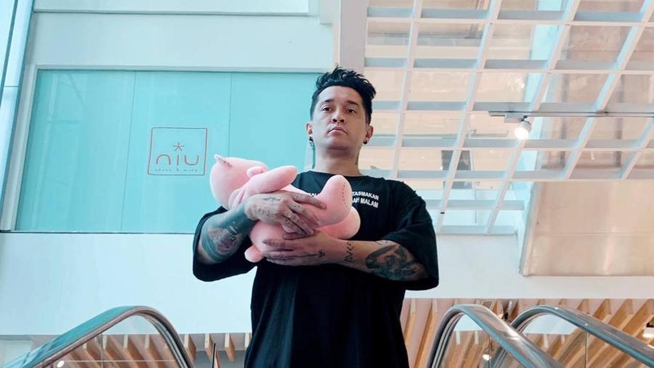 Pertanyaan muncul, apakah Miller memakai kolor di balik kaosnya. Lihat kejenakaannya memeluk boneka di eskalator, gaya yang bikin senyum.