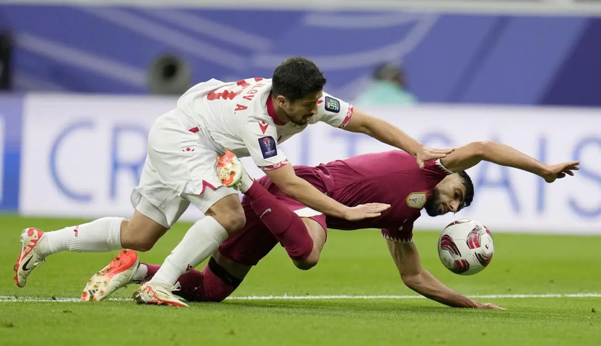 Pemain Qatar, Tarek Salman, berebut bola dengan pemain Tajikistan, Dzhalilov Alisher, pada laga Grup A Piala Asia di Stadion Al Bayt , Rabu (17/1/2024). (AP Photo/Aijaz Rahi)