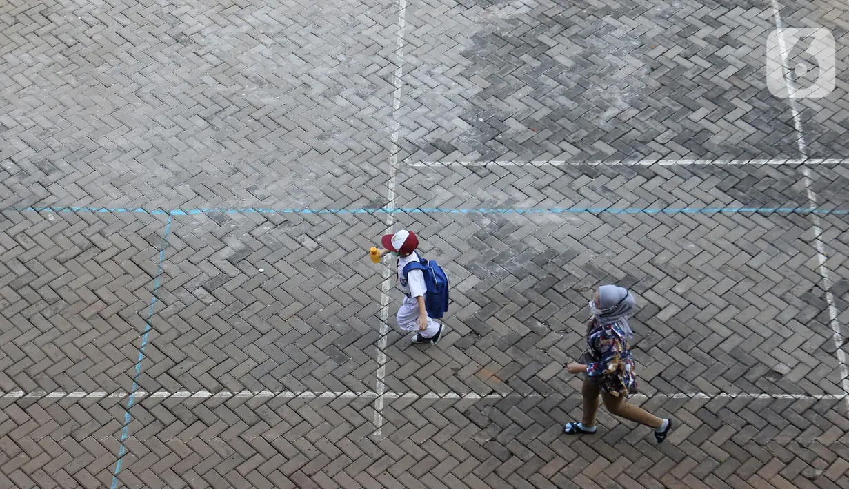 Seorang siswa didampingi orang tuanya tiba di SDN 05 Kalisari, Jakarta, Senin (30/8/2021). Pemprov DKI Jakarta menggelar pembelajaran tatap muka di tengah pandemi covid-19 mulai 30 Agustus 2021 secara terbatas dengan kapasitas 50 persen pada setiap satuan pendidikan. (Liputan6.com/Herman Zakharia)