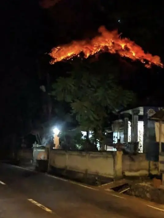 Lava pijar Gunung Agung menyembur dari puncak gunung di Karangasem, Bali, Senin (2/7). Gunung Agung melontarkan lava pijar sejauh 2 kilometer dan membuat hutan di sekitar Gunung Agung terbakar. (Handout / Badan Nasional Penanggulangan Bencana / AFP)
