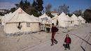 Anak-anak berjalan melewati tenda-tenda di sebuah kamp pengungsian di Antakya, Turki Selatan, pada tanggal 22 Februari 2023. Gempa berkekuatan 6,4 skala Richter mengguncang provinsi selatan Turki, Hatay, dan Suriah utara, menewaskan enam orang dan memicu kepanikan baru setelah gempa besar pada 6 Februari yang menewaskan hampir 45.000 orang di kedua negara tersebut. (Sameer Al-DOUMY/AFP)