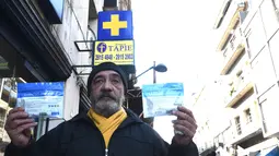Seorang pria menunjukkan dua kemasan ganja yang baru dibeli di apotek di Montevideo, Uruguay (19/7). Uruguay menjadi yang pertama di dunia yang secara resmi melegalkan produksi dan penjualan ganja. (AFP Photo/Miguel Rojo)