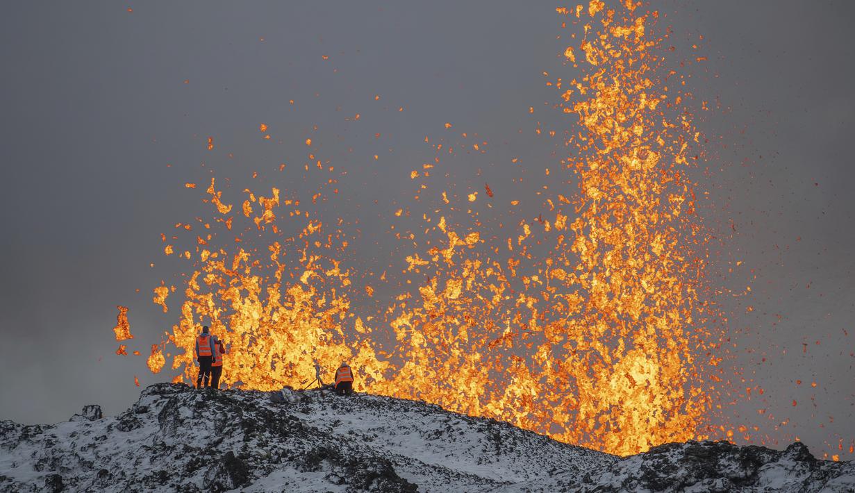 Ilmuwan dari Universitas Islandia melakukan pengukuran dan sampel dengan berdiri di punggung bukit di depan bagian aktif celah letusan gunung berapi aktif di Grindavik di Semenanjung Reykjanes Islandia, Selasa (19/12/2023). (AP Photo/Marco Di Marco)