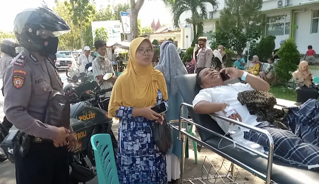 Polisi membantu mengevakuasi pasien setelah gempa Magnitudo 6,2 merusak sebuah rumah sakit lokal di Pasaman Barat, Sumatera Barat, Jumat (25/2/2022). Sejumlah bangunan rusak akibat guncangan gempa. (IDENVI SUSANTO/AFP)
