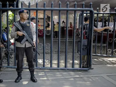 Polisi bersenjata lengkap berjaga di Gereja Katedral, Jakarta, Jumat (30/3). Penjagaan dilakukan untuk mengamankan misa Jumat Agung serta memberi kenyamanan kepada jemaat saat beribadah. (Liputan6.com/Faizal Fanani)