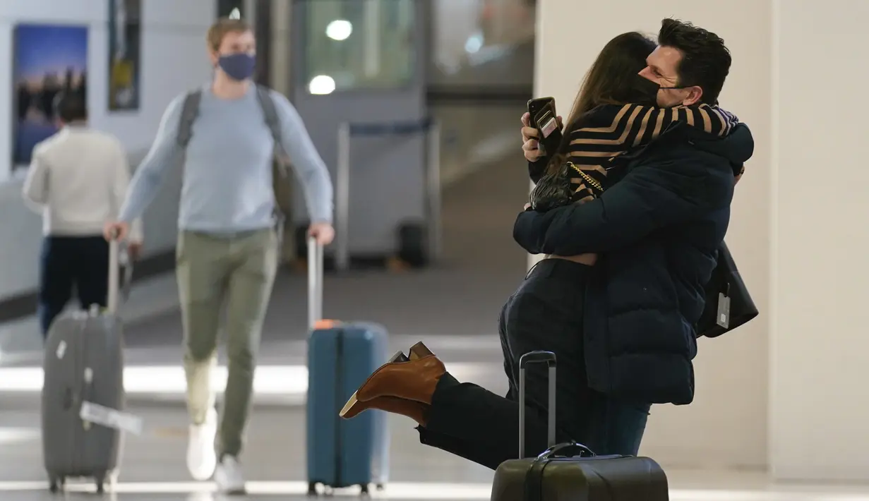 Natalia Abrahao diangkat tunangannya Mark Ogertsehnig saat mereka bertemu kembali di Bandara Internasional Newark Liberty di Newark, New Jersey, Senin (8/11/2021). AS membuka kembali perbatasannya mulai Senin untuk pengunjung asing, mengakhiri larangan masuk selama 20 bulan. (AP Photo/Seth Wenig)