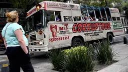 Pejalan kaki melihat bus "Corruptour" di Mexico City, Meksiko, 5 Februari 2017. Bus yang telah dimodifikasi itu mengajak penumpang mengunjungi 10 ikon kota, Meksiko City, yang dianggap sebagai pusatnya korupsi, kolusi, dan nepotisme. (YURI CORTEZ/AFP)