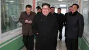 Gambar yang dirilis Kamis (25/1), memperlihatkan pemimpin Korea Utara, Kim Jong-un tersenyum sambil berjalan keliling pabrik farmasi di Pyongyang. Obat-obatan menjadi salah satu komoditi yang dijual Korut guna mendanai proyek nuklir. (KCNA VIA KNS/AFP)