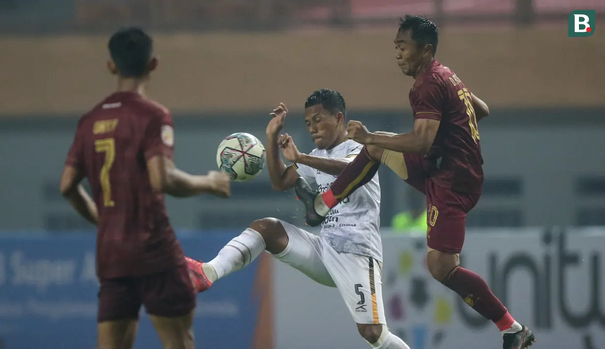 Pemain Rans Cilegon FC, Saddam Hi Tenang (tengah) berebut bola dengan pemain Sriwijaya FC, Dedi Hartono dalam laga matchday ke-3 Grup X Babak 8 Besar Liga 2 2021 di Stadion Wibawa Mukti, Cikarang, Rabu (22/12/2021). (Bola.com/Bagaskara Lazuardi)