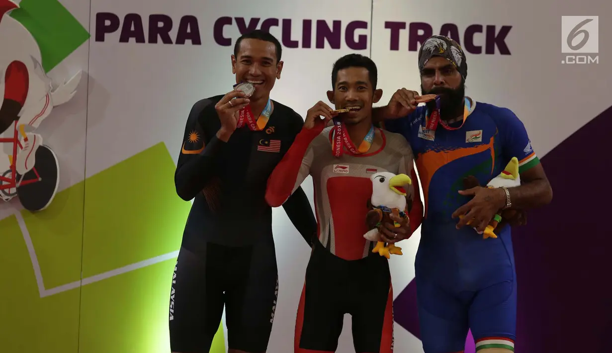 Pebalap sepeda Indonesia, M. Fadli Imammuddin  bersama pebalap Malaysia Mohd Najib dan Singh Harinder dari India mengigit medali usai bertanding  pada nomor 4000 meter individual pursuit C4, Jakarta Timur, Jumat (12/10). (Merdeka.com/Imam Buhori)