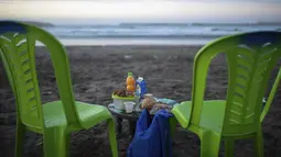 Makanan dan minuman diletakkan di atas meja untuk pasangan saat mereka bersiap untuk berbuka puasa di tepi pantai, di Rabat, Maroko, Sabtu (23/4/2022). Untuk pertama kalinya dalam dua tahun sejak pandemi COVID-19, orang-orang dapat menghidupkan kembali tradisi Ramadhan dengan berkumpul dan berbuka puasa di tempat umum. (AP Photo/Mosa'ab Elshamy)