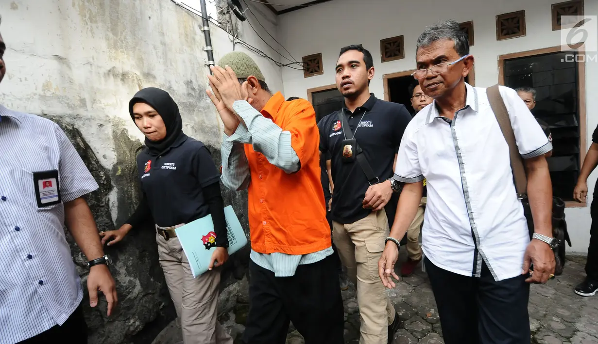 Tersangka penampung TKI Ilegal bersama petugas usai melakukan penggeledahan di dalam rumah di Jalan Percetakan Negara X, Jakarta, Rabu (31/5). Petugas Dirtipidum Mabes Polri melakukan pencarian barang bukti baru. (Liputan6.com/Helmi Fithriansyah)