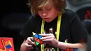 Seorang anak laki-laki serius memecahkan permainan rubik pada kejuaraan kubus Rubik Dunia di Melbourne, Australia (12/7/2019). Permainan Kubus Rubik 3x3x3, ditemukan oleh Profesor Rubik dari Hongaria pada tahun 1974. (AFP Photo/William West)