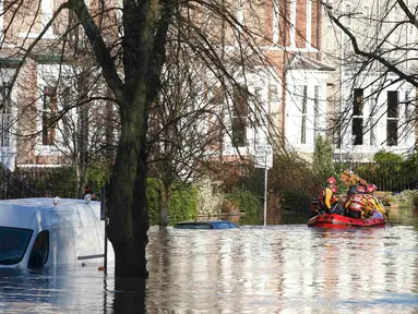 Tim regu penyelamat menyisir lokasi pemukiman warga yang terendam banjir menggunakan perahu karet di York, Inggris utara, Minggu (27/12). Banjir akibat luapan sungai Ouse yang telah memperburuk sejumlah wilayah Inggris utara. (REUTERS/Phil Noble)