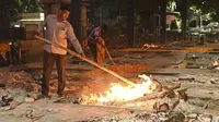 Staf memeriksa tumpukan kayu yang terbakar dari korban Covid-19 di Krematorium Nigambodh Ghat, New Delhi, Kamis (22/4/2021). India sekarang menjadi negara terparah kedua di dunia setelah AS, dengan kasus baru lebih dari 200.000 infeksi baru setiap hari selama sepekan terakhir. (Sajjad HUSSAIN/AFP)