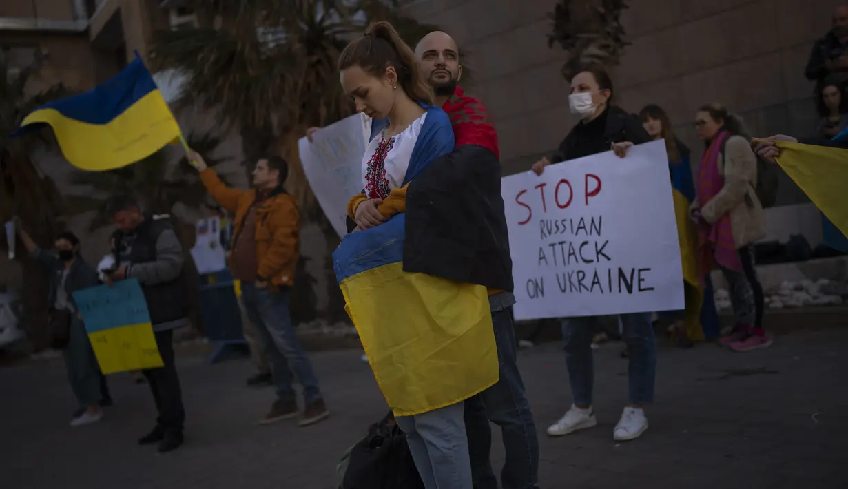 Demonstran memegang poster dan bendera saat mereka menghadiri protes pro-Ukraina di luar Kedutaan Besar Rusia, setelah pasukan Rusia melancarkan serangan yang diantisipasi mereka ke Ukraina, di Tel Aviv, Israel, Kamis, 24 Februari 2022. (AP Photo/Oded Balilty)