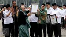 Ketua MURI Jaya Suprana memberikan piagam untuk pembacaan serentak 1 miliar shalawat Nariyah dan kirab terjauh kepada Ketum PBNU Said Aqil Siradj dalam Hari Santri Nasional di Monas, Jakarta, Sabtu (22/10). (Liputan6.com/Fery Pradolo)