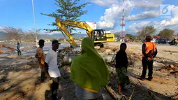 Seorang ibu bernama Lita menyaksikkan proses evakuasi anaknya, Nanang Kosim (20) menggunakan alat berat yang diduga masih tertimbun di dalam tanah pascagempa dan tsunami Palu di Pantai Talise, Sulawesi Tengah, Senin (8/10). (Liputan6.com/Fery Pradolo)