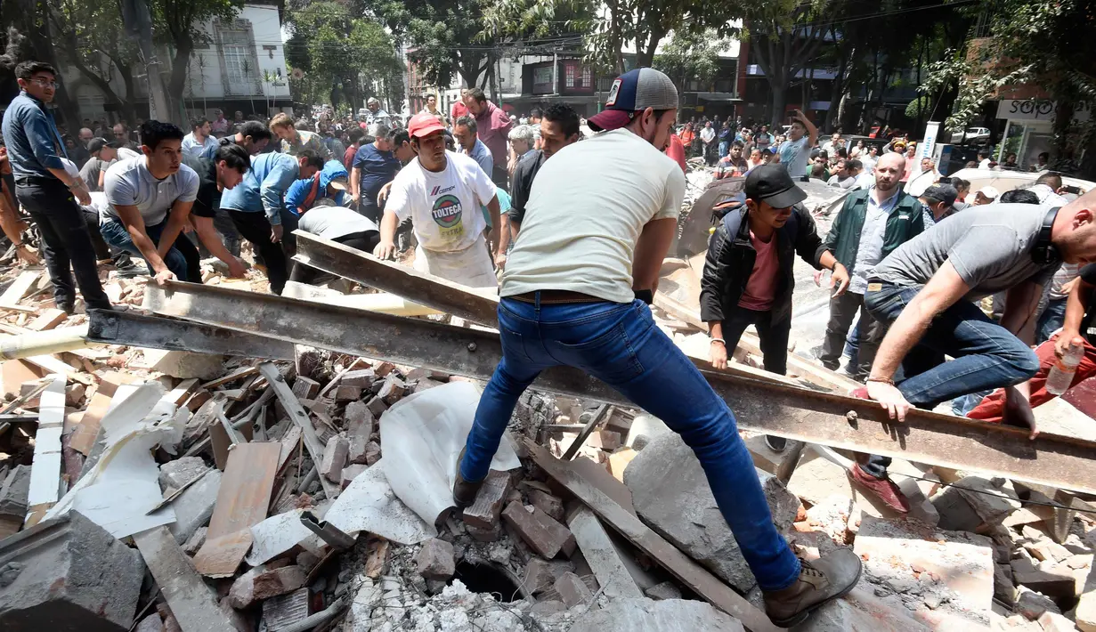 Warga memindahkan puing-puing bangunan untuk mencari korban akibat gempa 7,1 SR di Mexico City, Meksiko (19/9). Sejumlah fasilitas publik seperti bandara, mengalami kerusakan yang signifikan. (AFP Photo/Alfredo Estrella)