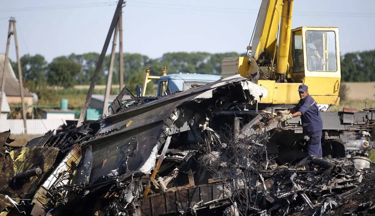 Salah satu anggota Kementerian Darurat Ukraina berusaha memindahkan serpihan puing pesawat MH-17 yang jatuh di desa Hrabove, Donetsk, Ukraina, (20/7/2014). (REUTERS/Maxim Zmeyev)