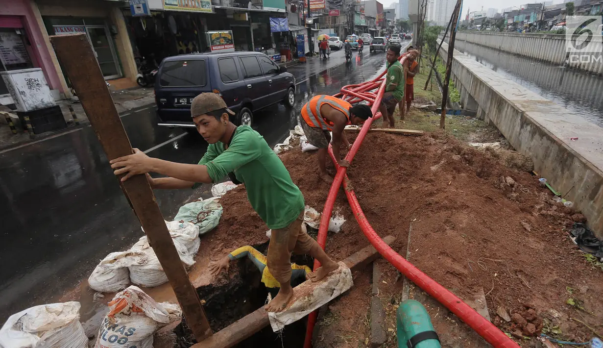 Pekerja merapikan kabel jaringan utilitas ke dalam tanah di kawasan Kemayoran, Jakarta, Minggu (14/1). PT PLN Disjaya akan menertibkan kabel listrik yang ada di tiang-tiang dengan menanam kabel di bawah tanah. (Liputan6.com/Immanuel Antonius)