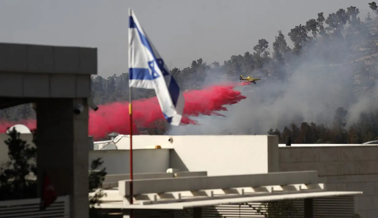 Sebuah pesawat pemadam kebakaran bekerja memadamkan api yang berkobar di kawasan hutan dekat Kibbutz Neve Ilan di sebelah barat Yerusalem, Israel, Rabu (9/6/2021). Kebakaran hebat di pinggiran Yerusalem melumpuhkan lalu lintas. (Ahmad GHARABLI/AFP)