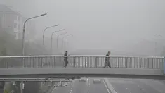 Orang-orang yang memakai masker melintasi jalan layang pada hari yang berkabut dan tercemar di Beijing, Sabtu (6/11/2021). Jalan raya dan taman bermain sekolah di Beijing ditutup pada Jumat (5/11) karena polusi kabut asap yang tebal, setelah China meningkatkan produksi batu bara. (JADE GAO/AFP)