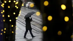 Pejalan kaki berjalan di tengah hujan di San Francisco (13/12/2021). Badai musim dingin besar yang melanda California Utara diperkirakan akan meningkat dan perjalanan transportasi tertunda serta ancaman banjir lokal setelah musim gugur yang tidak normal di AS Barat. (AP Photo/Jeff Chiu)